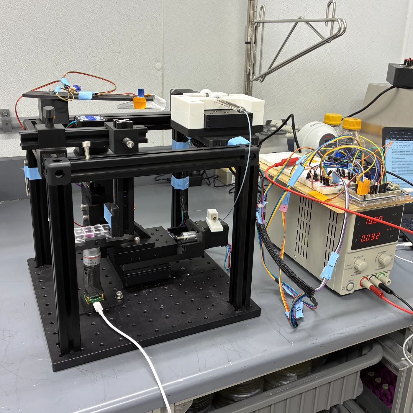 Custom automated bioprinting system with motion stages, electronics, and a sample plate.